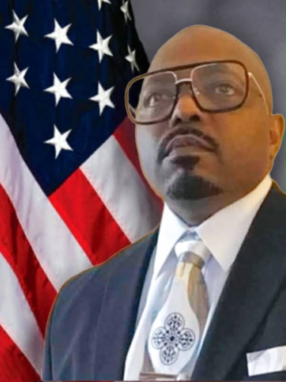Darius Robinson in a suit standing before the American flag